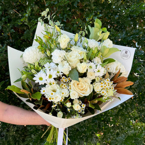 Bouquet of flowers held by a person against a green leafy background