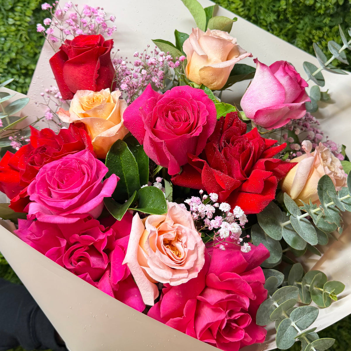 Bouquet of colorful roses with eucalyptus foliage on a green background