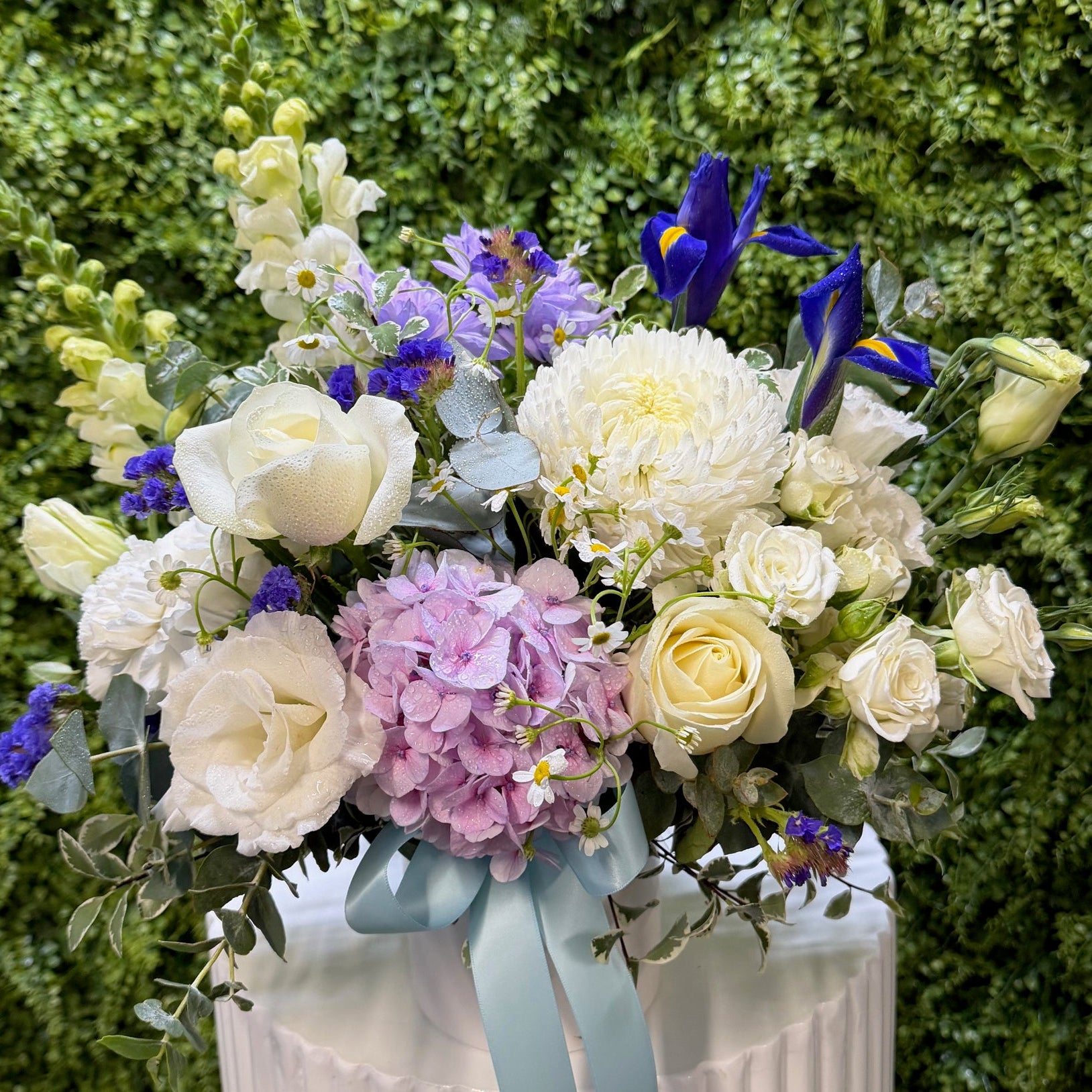Bouquet of flowers with white, blue, and pink colours on a green background