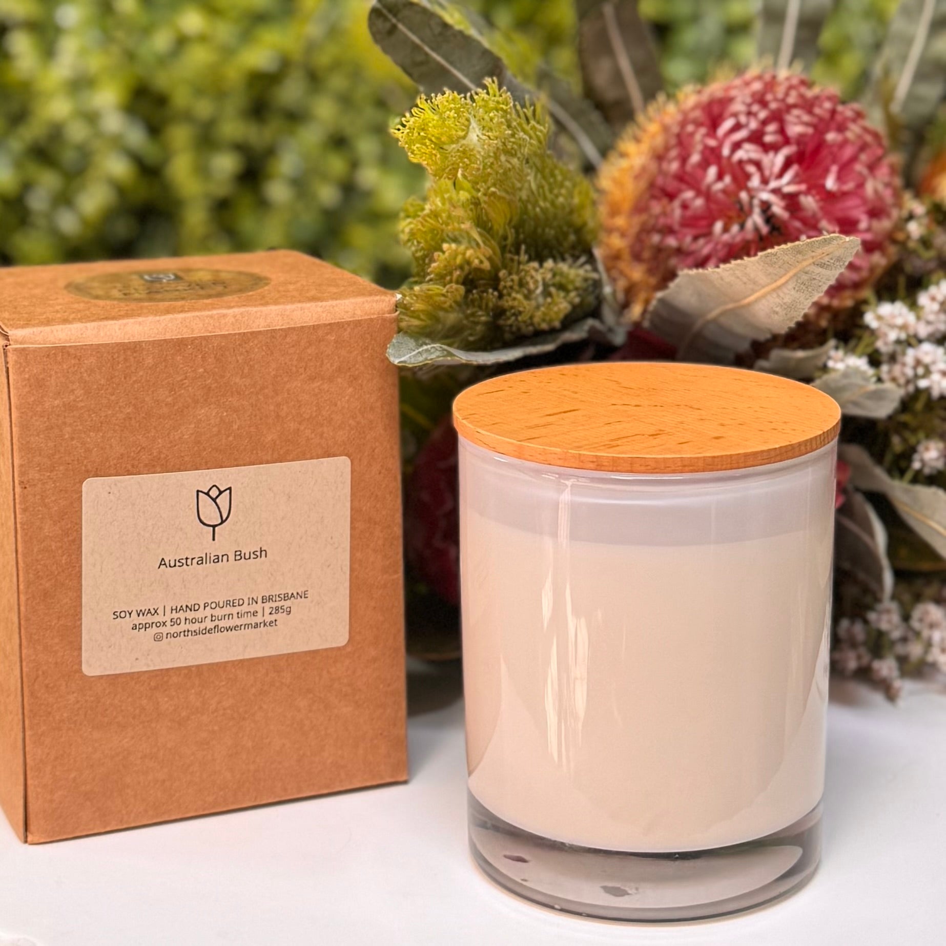 Candle with wooden lid and packaging labeled 'Australian Bush' against a natural background.