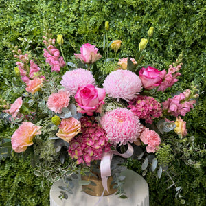Bouquet of pink and green flowers in a rose gold ceramic container on a green background