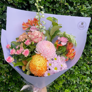 Bouquet of pastel flowers with a Northside Flower Market logo against a green leafy background