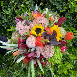 Colorful wedding bouquet of flowers with sunflowers and other varieties against a green leafy background