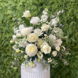 Bouquet of white flowers in a white vase against a green textured background